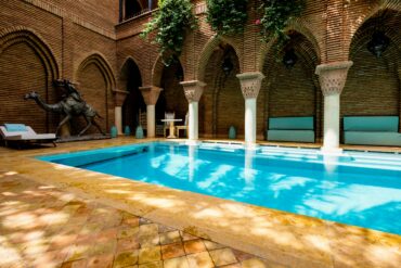 Luxury Moroccan resort pool with sun loungers and palm trees, embodying serene relaxation and digital disconnection in Marrakech.