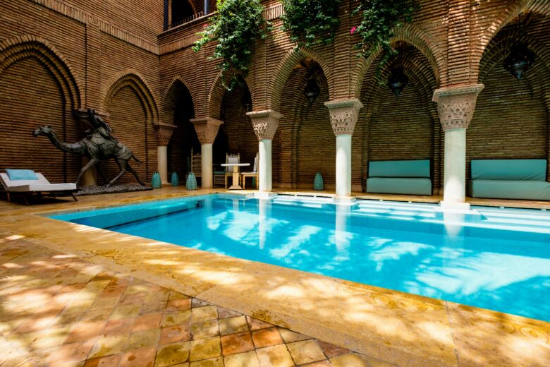 Luxury Moroccan resort pool with sun loungers and palm trees, embodying serene relaxation and digital disconnection in Marrakech.