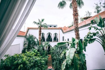 Luxury wellness retreat in Marrakech, Morocco: Serene woman practicing yoga in a lush resort garden, combining authentic Moroccan spa and meditation for holistic well-being.