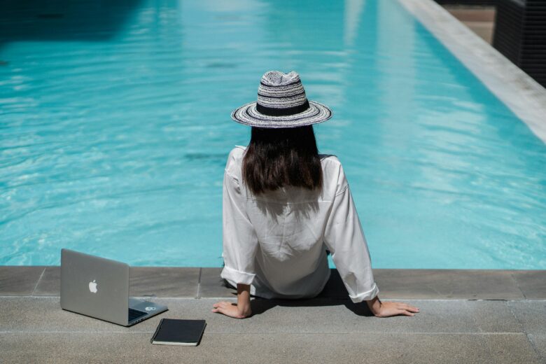 Digital nomad working on laptop at a luxurious all-inclusive Moroccan resort by the pool, ideal for remote work and telework in Morocco.
